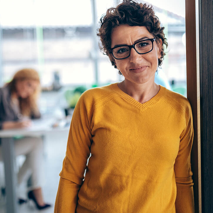 Frau mit Brille lehnt an der Wand